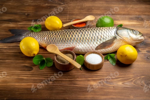Preview: front view fresh fish with lemon and seasonings on wooden desk ocean sea food seafood