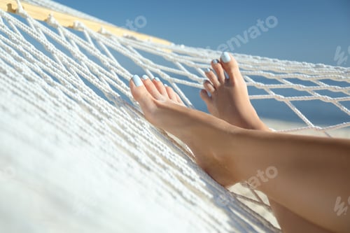 Preview: Young woman relaxing in hammock on beach, closeup