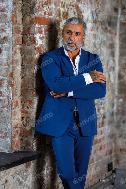Preview: A man in a blue formal suit on a brick background. Portrait of a businessman.