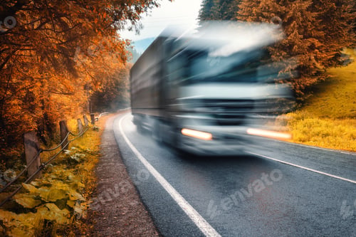 Preview: Blurred truck on the road in autumn foggy forest in rainy day
