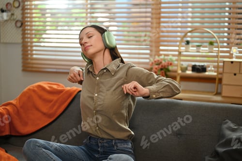 Preview: Happy millennial woman listens to favorite podcast music in headphones and relaxing on sofa at home