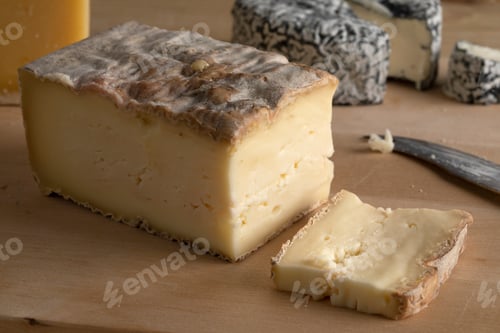 Preview: Piece of Italian Taleggio and a slice on a cutting board close up
