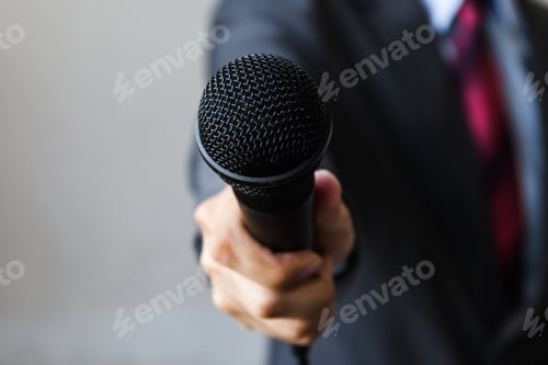 Preview: Man in business suit holding a microphone