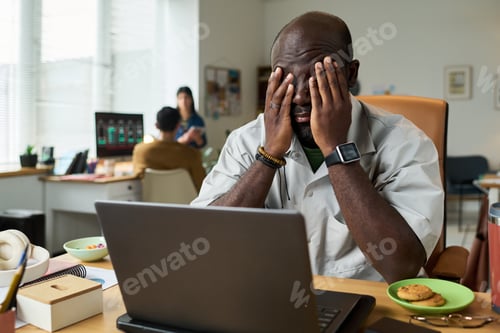 Preview: Black Man Sitting at Desk Feeling Stressed While Working Remotely