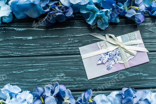 Preview: top view of wooden green background with blue floral borders and envelope