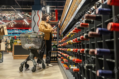 Preview: a woman with a trolley makes purchases in a supermarket