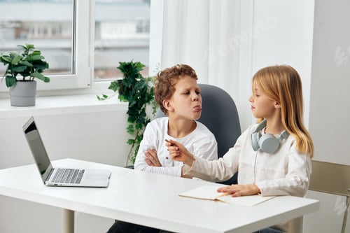 Preview: Happy Caucasian siblings studying at home using a laptop for online elearning The boy and girl are