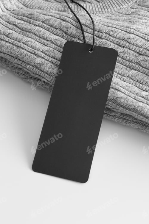 Preview: Black clothing tag mockup on a grey sweater.