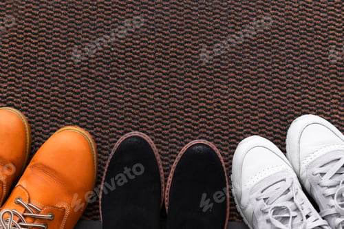 Preview: Different men's and women's shoes, pair of sneakers on a shoe mat, top view.