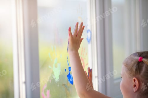 Preview: Children girl draw with palms on the window. Painted hands leave a mark on the glass.