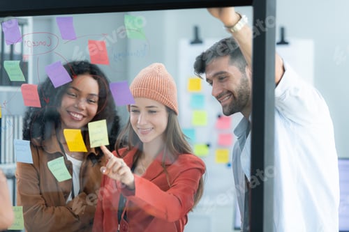 Preview: Multiethnic young business people brainstorming on a project by writing on the glass wall