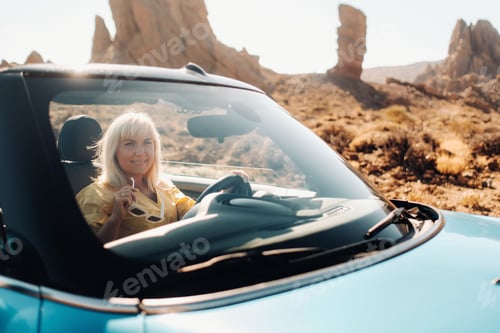 Preview: Girl in yellow dress enjoying a road trip in a convertible through a deserted valley with mountains