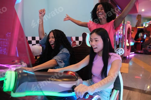 Preview: Excited female friends playing arcade racing game together