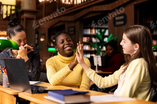 Preview: Satisfied teenagers students doing high five next to tutor in the library