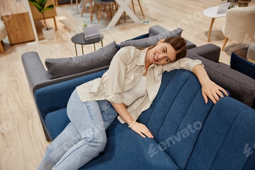 Preview: Young woman looking for new sofa couch at furniture store