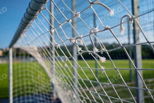 Preview: closeup of soccer gate goalpost white rope net with green field in background