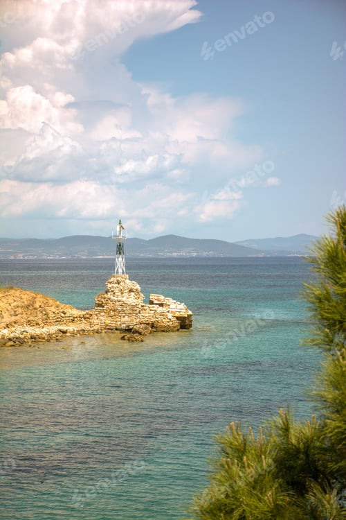 Preview: Stunning lighthouse situated atop a rocky outcrop jutting out into the sparkling blue waters