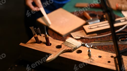 Preview: Various leather craft tools and material on a workbench. Close up shot