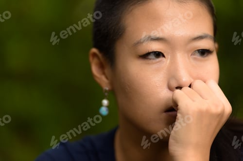 Preview: Close-up portrait of beautiful rebel Asian woman face thinking outdoors
