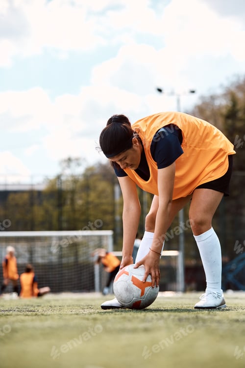 Preview: Female soccer player preparing to kick the ball.