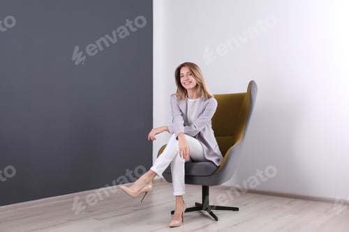 Preview: Young woman sitting in armchair at home. Space for text