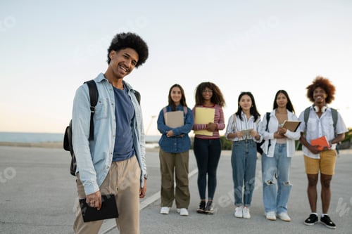 Preview: Multiracial group of six students posing together with college notebooks and books.