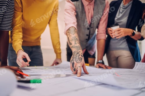 Preview: Multiracial team of architects having a meeting while using blueprints
