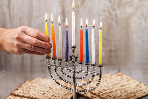 Preview: Menorah with candles for Hanukkah on a light wooden background. Matza in the background.