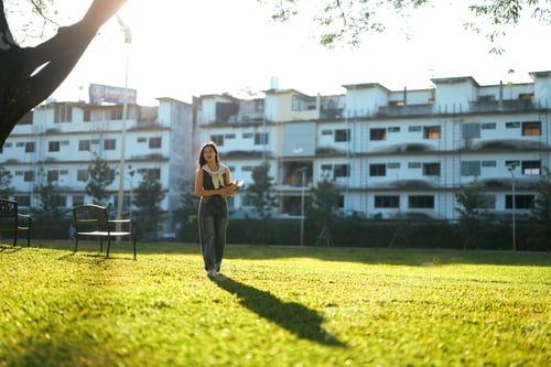 Visualização: Jovem estudante asiática caminhando pelo parque do campus