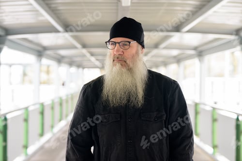Preview: Mature bearded man with eyeglasses thinking at footbridge in the city