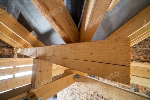 Preview: Attic of a building under construction with wooden beams of a roof structure and brick walls