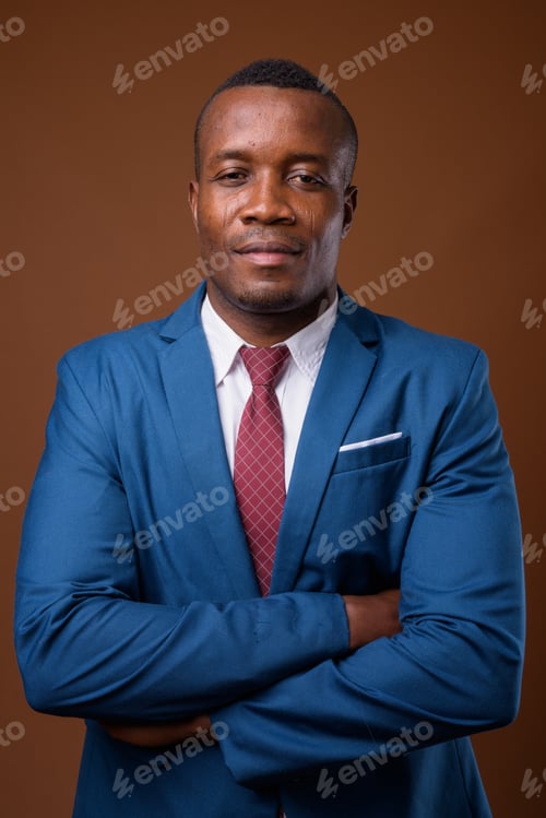 Preview: Studio shot of young African businessman against brown backgroun