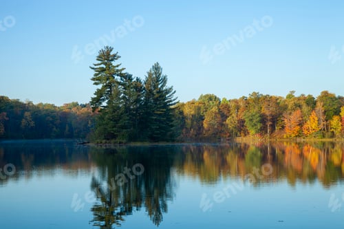 Preview: Beautiful calm lake with trees in autumn color and a small island in northern Minnesota at dawn
