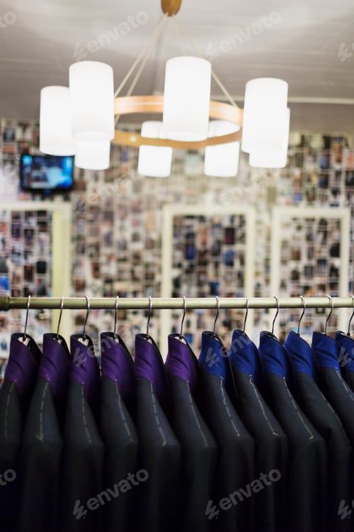 Preview: Illuminated pendant light hanging over suit rack in clothing store