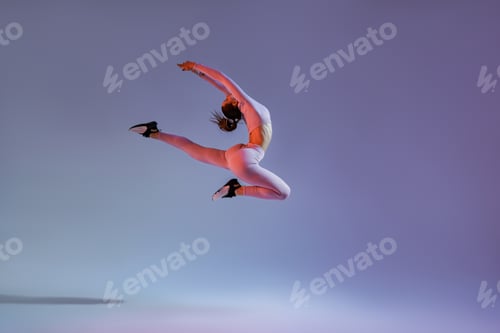 Preview: Sporty girl jumping doing split leap in air with joyful expression. Flexible and weightless concept