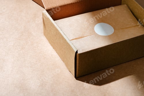 Preview: A sealed kraft box containing a wrapped item, positioned on a textured brown surface for an unboxing