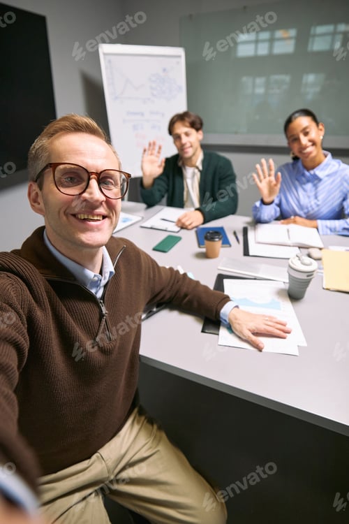 Preview: Portrait of Young Caucasian Man Taking Selfie with Diverse Colleagues Waving