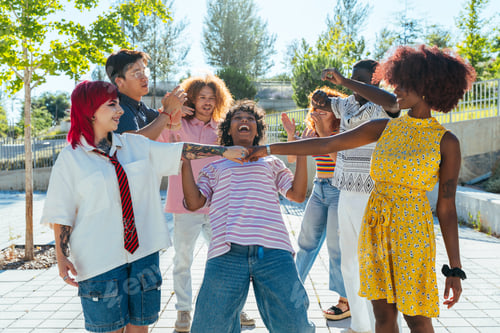 Preview: Multiethnic group of young friends meeting and having fun outdoors