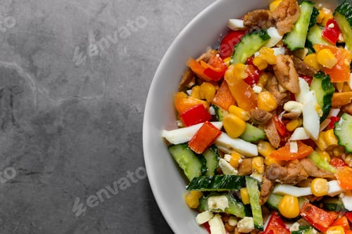 Preview: Bright vegetable salad with chicken on a gray concrete background.