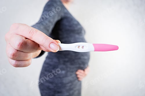 Preview: Young pregnant woman with swollen belly holding a pregnancy test