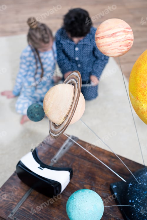 Preview: model of the solar system and Virtual reality headset on table with children behind