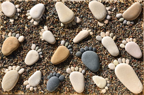 Preview: Pebble stones arranged like footprints on the beach. Family summer vacation concept