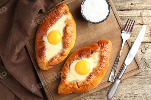 Preview: Tasty khachapuris with cheese and eggs served on wooden table, flat lay