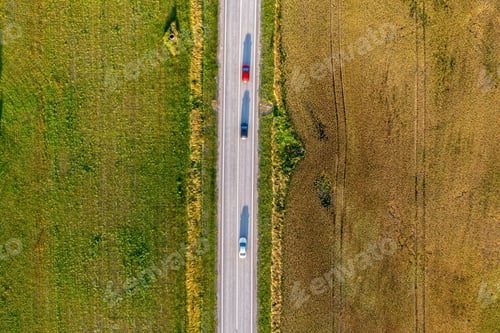 Preview: Aerial View of Cars Driving on Rural Road Through Green and Brown Fields