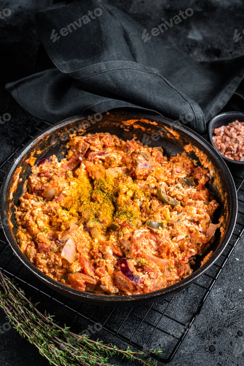 Preview: Turkish Menemen omelet in a frying pan. Black background. Top view