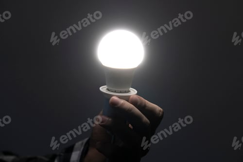 Preview: a hand holding a shining light bulb in the dark space in the night