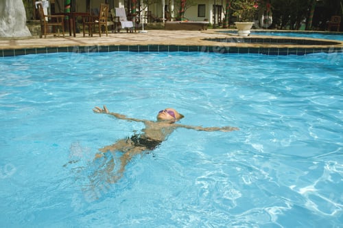Preview: Asian Child Floating on Back in Swimming Pool Relaxing during Summer Day