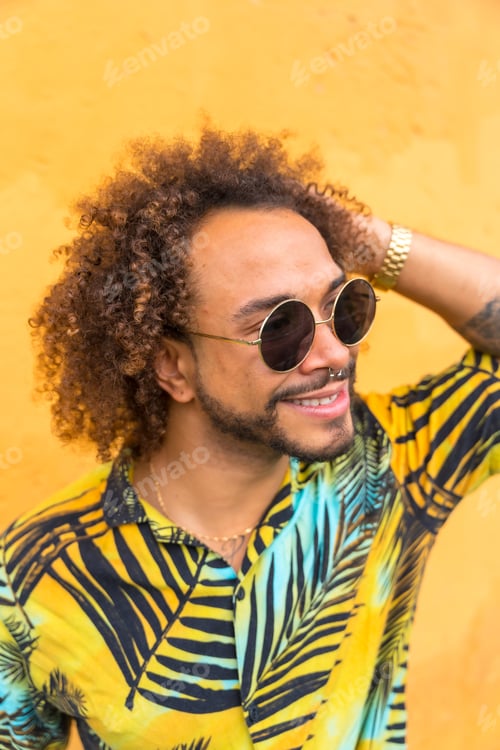 Preview: Portrait of an attractive man with afro hair in summer summer in a palm tree shirt on a yellow