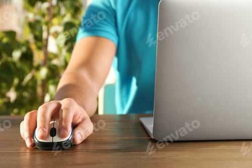 Preview: Man using computer mouse with laptop at table, closeup