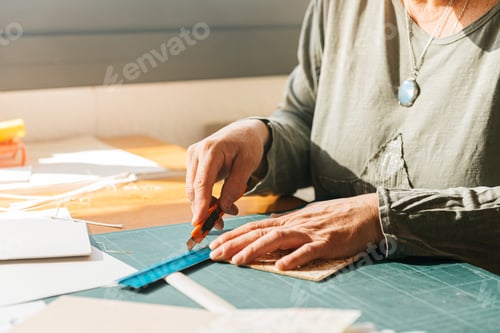 Preview: Unrecognizable woman using cutting blade scale on hardcover at table in daylight